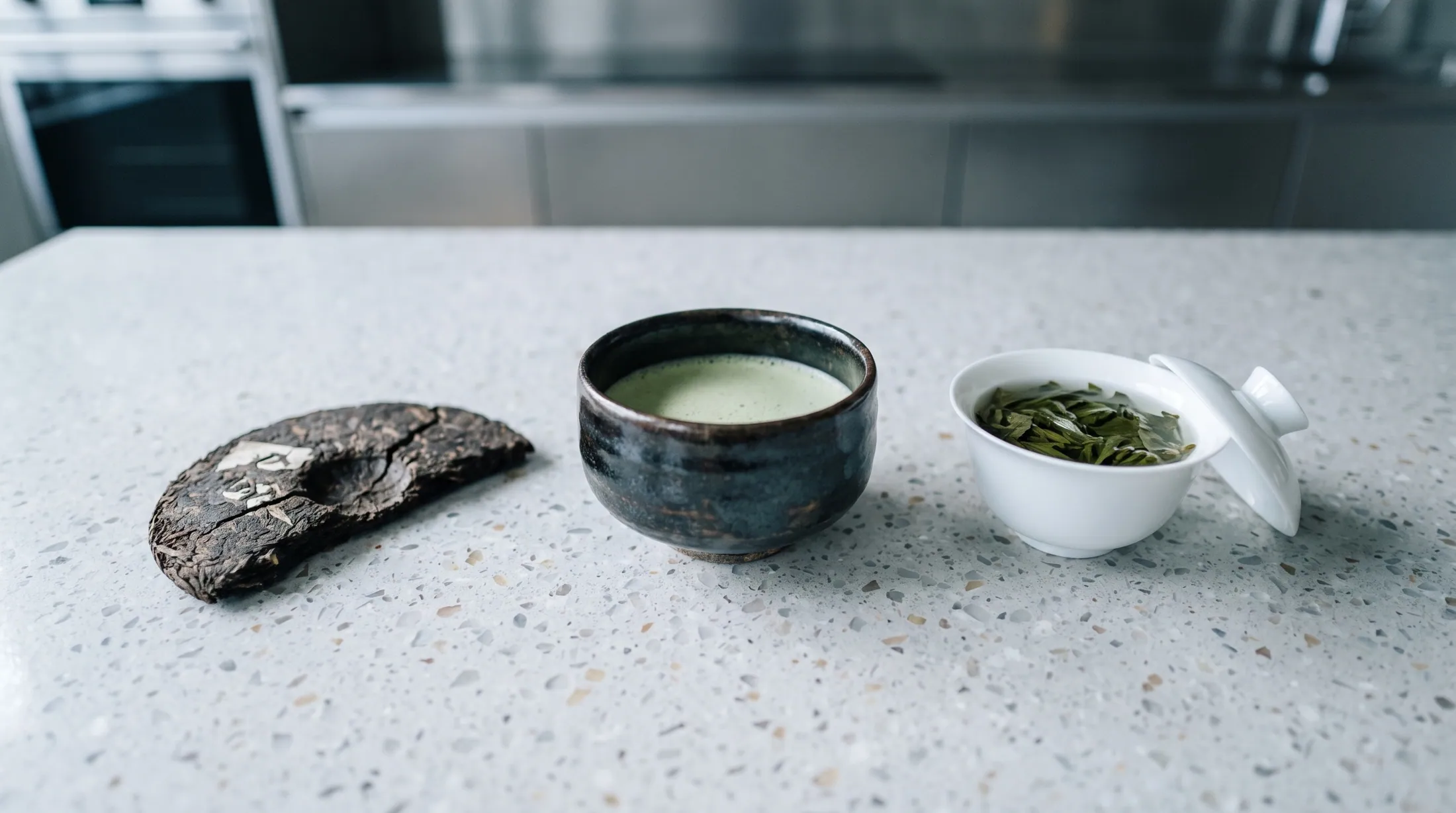 A piece of old pressed tea cake, a dark bowl of whisked tea and a gaiwan of loose leaf: three eras of drinking tea.